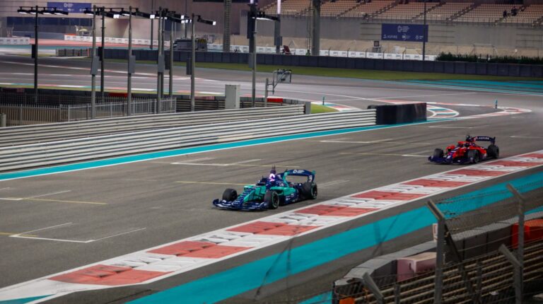A Human vs AI demo at Yas Marina Circuit in Abu Dhabi, with two race cars driving down a straight.