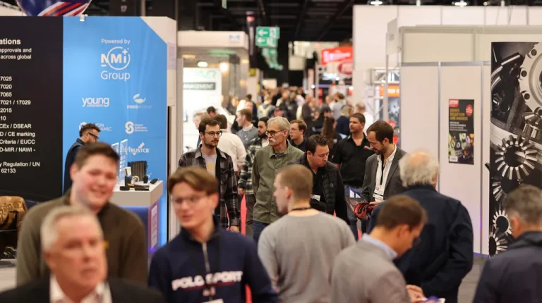 The busy show floor or PMW Expo exhibition, with people walking between long cordidor or stalls and stands.