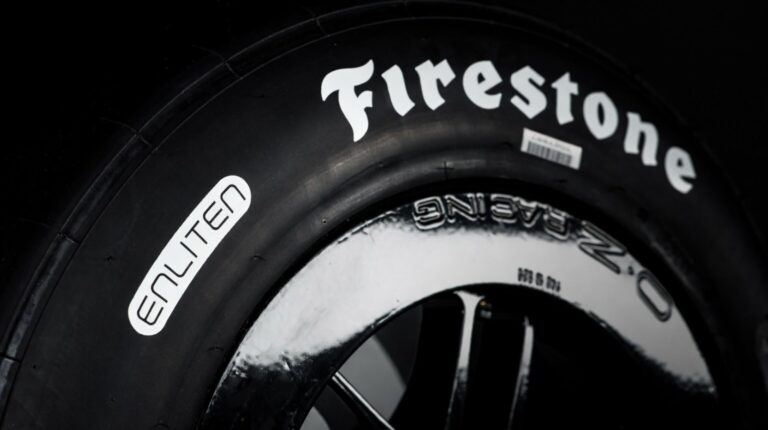 A black tire with Firestone and Enliten written along the sidewall in white.